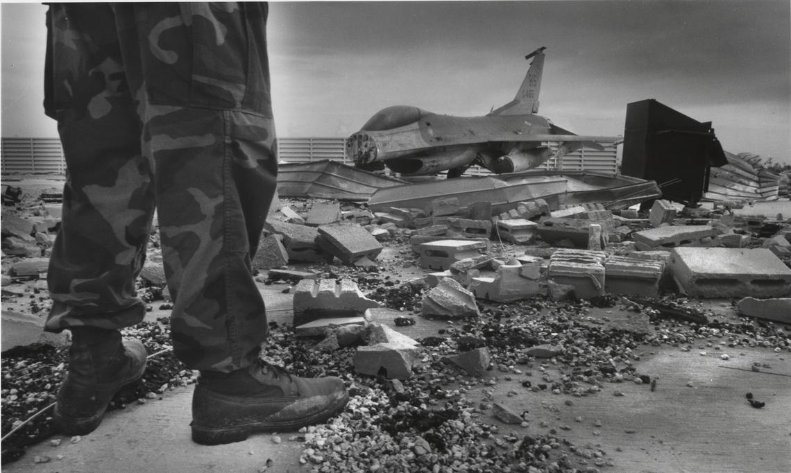 A service member stands amid the rubble of Homestead Air Force Base, including F-16 aircraft scattered by Hurricane Andrew in August 1992.