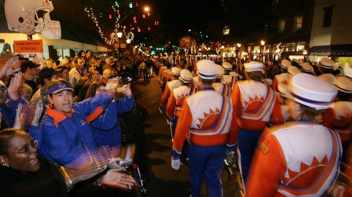 University of Florida fans do the Gator chomp as the Fightin’ Gator Marching Band marches past during a pre-game block party in 2007.