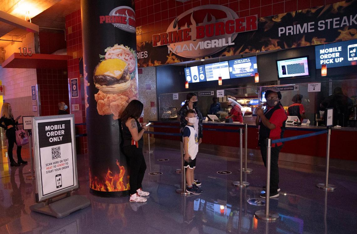 Fans wearing protective mask waiting for pick up their food at Brim Burger before the start of an NBA basketball game between the Miami Heat against the Golden State Warriors at the AmericanAirlines Arena on Thursday, April 1, 2021 in Miami, Fl. The Heat increase the number of fans allowed to attend games at AmericanAirlines Arena to about 4,000 just about 20 percent of the building’s usual capacity of 19,600.