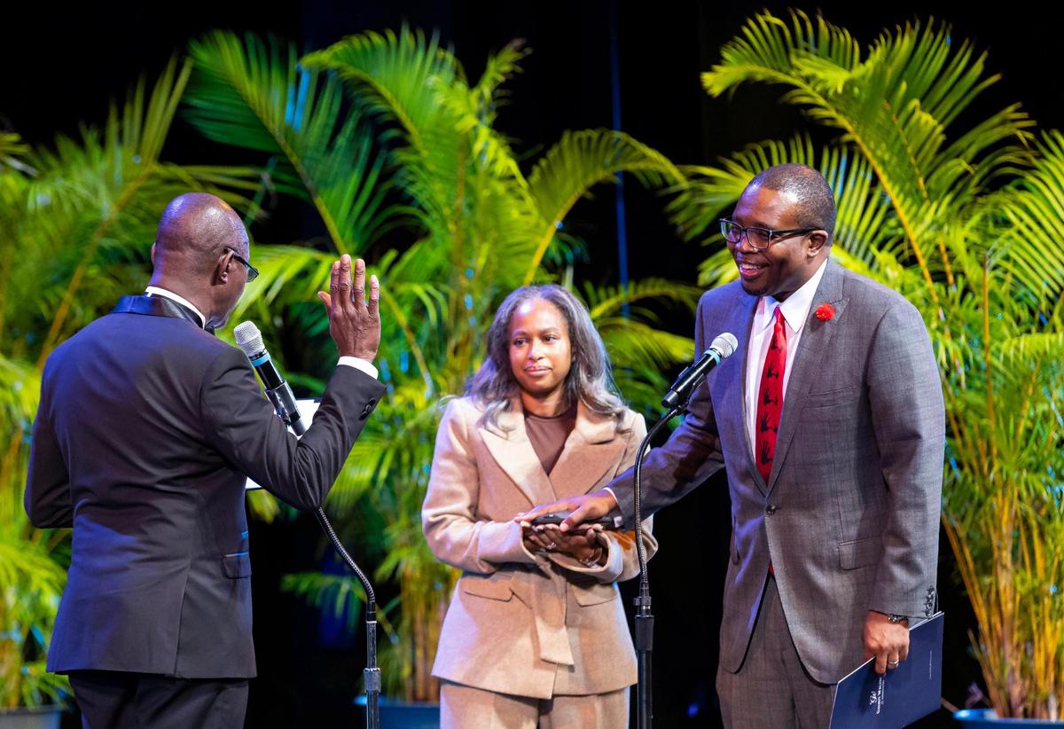 Newly elected North Miami Beach Mayor Michael Joseph, far-right, alongside his wife, Asia Jospeh, is sworn in by Nelson Voltaire, left, who runs Radio Piman Bouk, during a ceremony at the Julius Littman Performing Arts Theater on Tuesday, Dec. 10, 2024, in North Miami Beach, Fla.