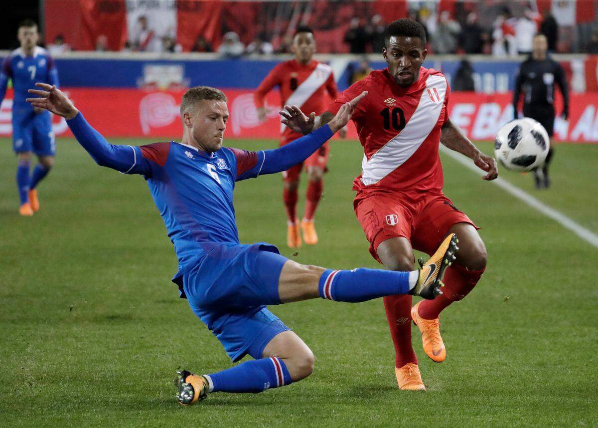 In this photo taken on Tuesday, March 27, 2018, Iceland defender Ragnar Sigurdsson, left, clears the ball as Peru forward Jefferson Farfan attacks during the first half of an international friendly soccer match in Harrison, N.J. (AP Photo/Julio Cortez)