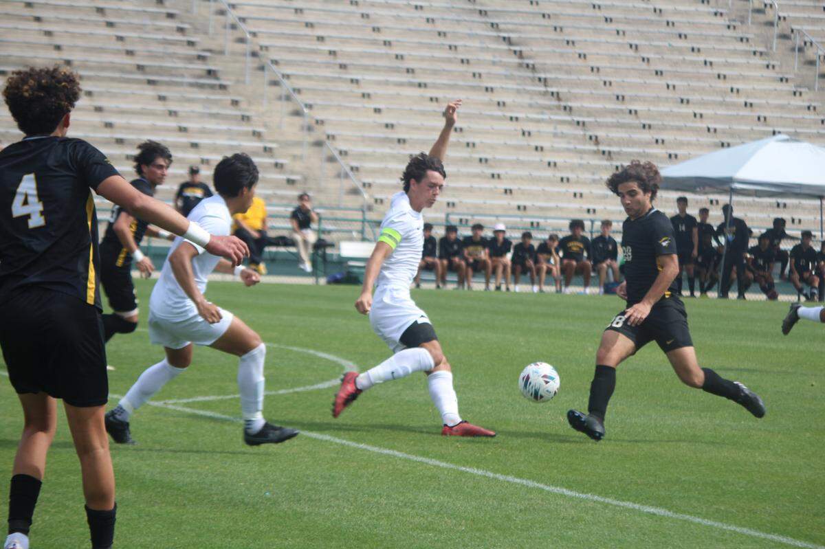 American Heritage’s Agustin Covos (28) lets go of a shot as Naples defender Harvey Sarajian closes in during Saturday’s Class 5A boys’ soccer state championship match in DeLand.