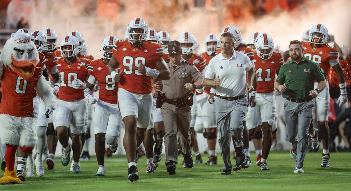 The Miami Hurricanes rush the field for the start of an NCAA football game against the Notre Dame Fighting Irish at Hard Rock Stadium in Miami Gardens, Florida, on Sunday, August 31, 2025.