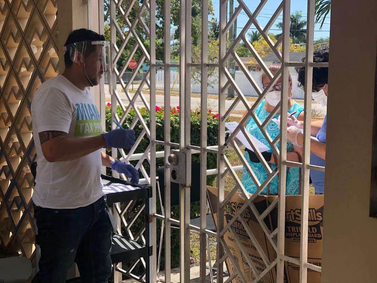 Community members in need of assistance from Miami Tax Pros, a coalition of volunteer tax preparers, drop off paperwork at a Florida City site.