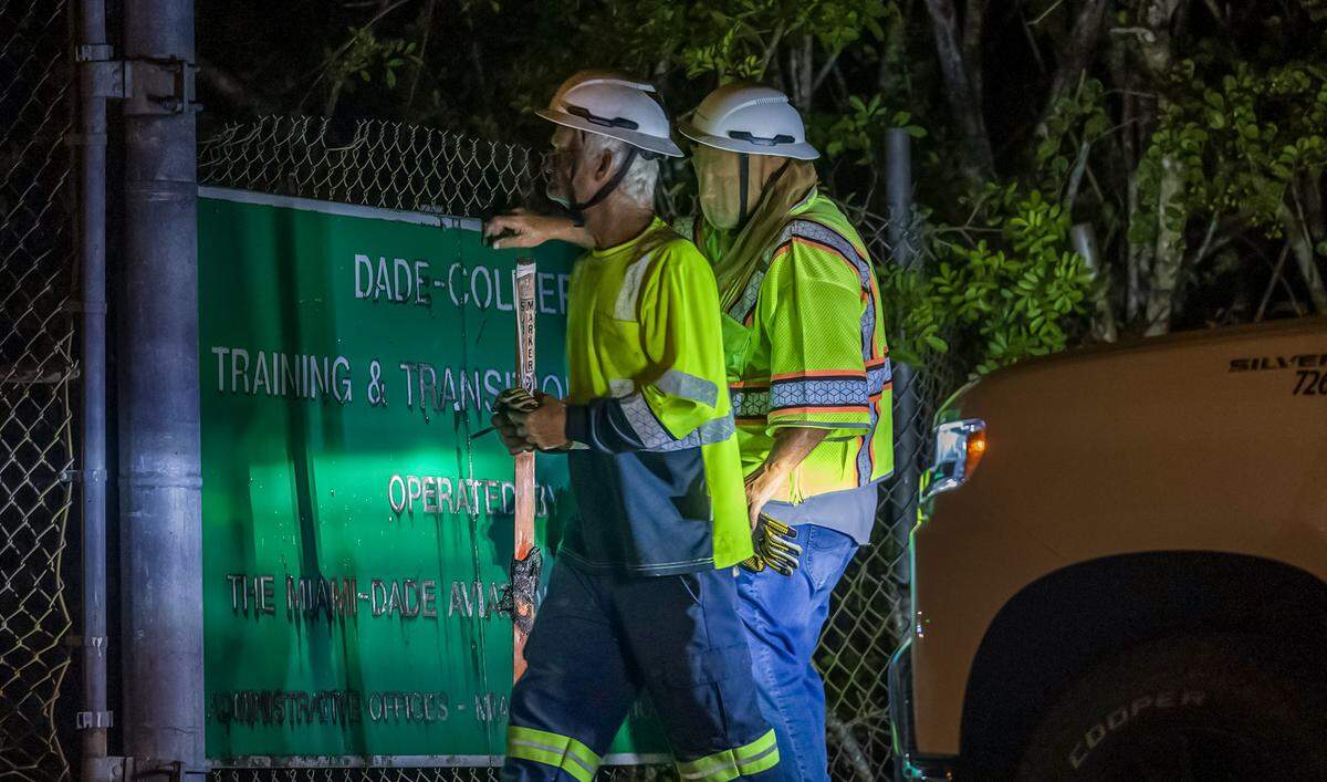 Two workers prepare to cover the Dade-Collier Training and Transition Airport with the “Alligator Alcatraz,” sign at the entrance of the migrant detention center, in Ochopee, Florida on Wednesday July 02, 2025.