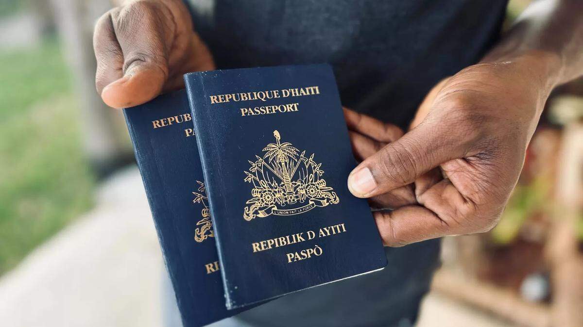 A Haitian migrant who recently arrived in South Florida through the Biden parole program with his girlfriend holds their passports. 