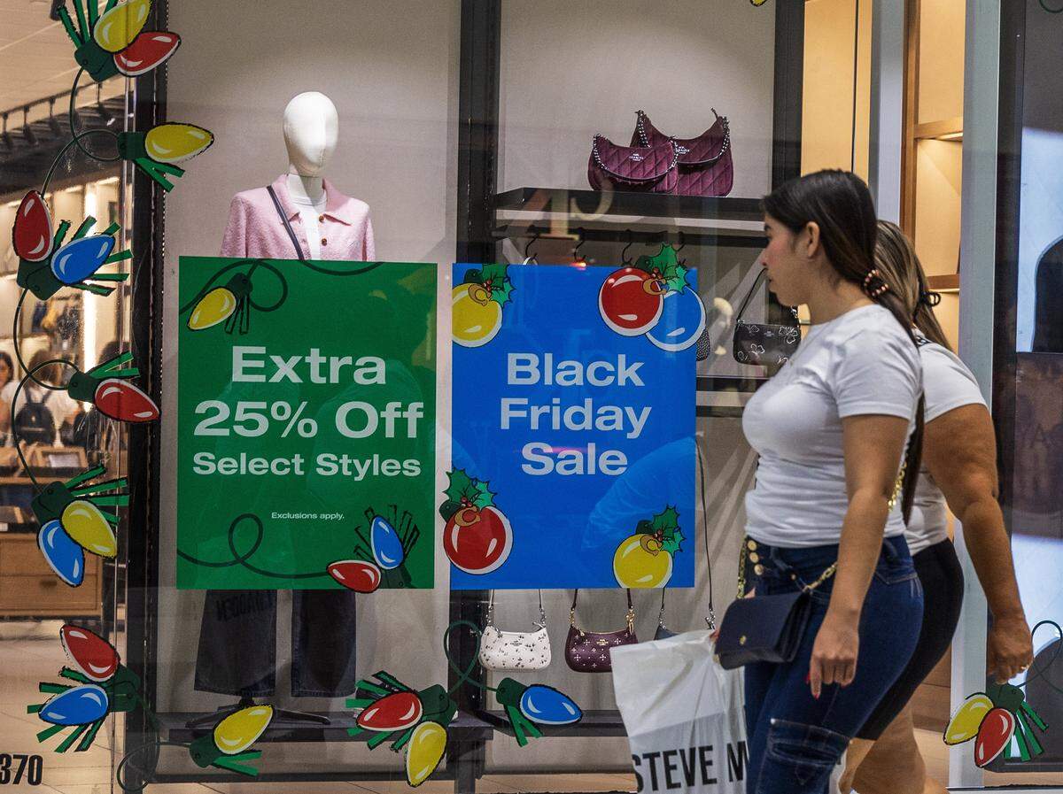 Shoppers walk by sales signs at the Coach store in the Dolphin Mall in Sweetwater on Friday, Nov. 21, 2025.