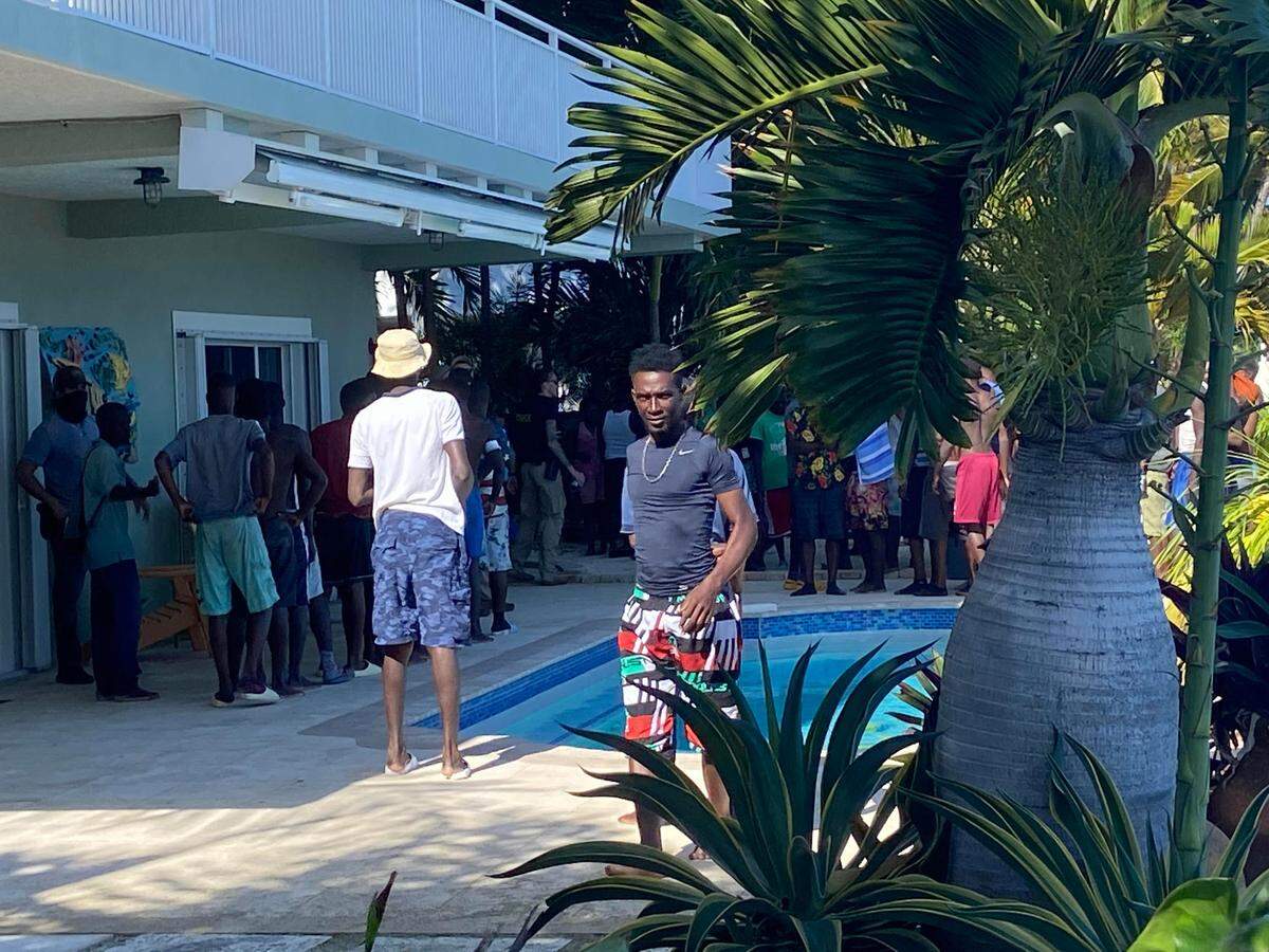 A group of men and women who migrated from Haiti on an overloaded sailboat, stand in the backyard of an oceanfront home on Key Largo Tuesday, Jan. 2, 2022.