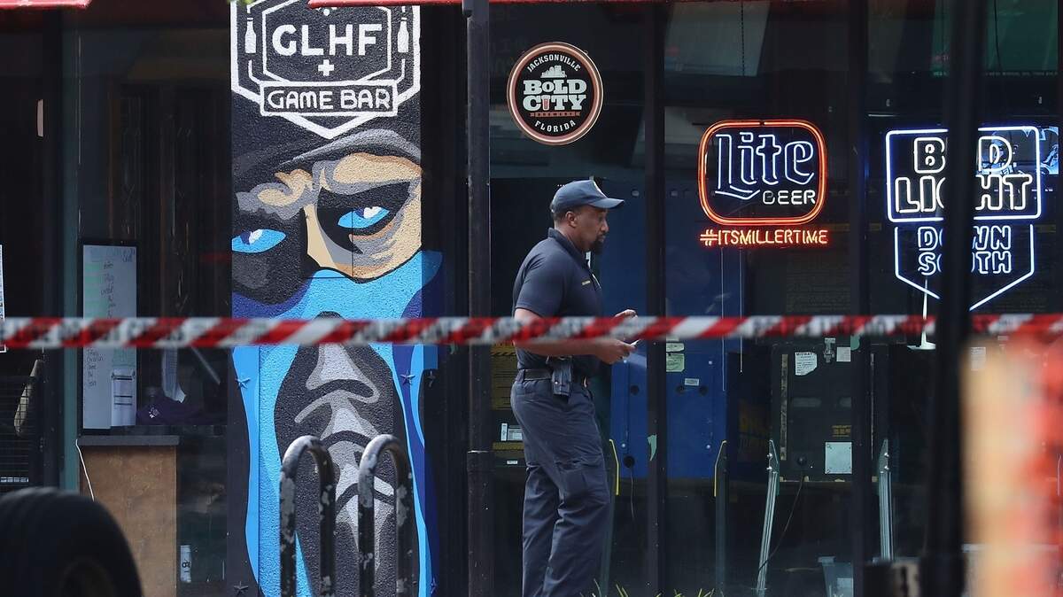 An officer with the Jacksonville Sheriff’s Office walks past the GLHF Game Bar, where 3 people, including the gunman, were killed at the Jacksonville Landing on Sunday in Jacksonville, Florida.