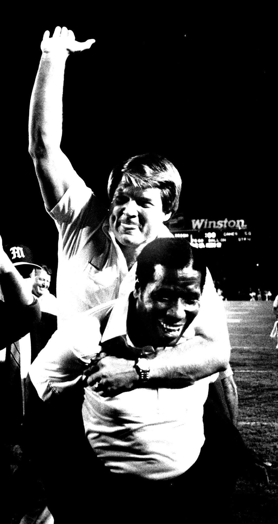 In 1985, Miami Hurricane coach Jimmy Johnson raises his hand high in victory after jumping on the back of his assistant coach Alexander Hubbard after the Hurricanes defeated Notre Dame 58-7 in the Orange Bowl.
