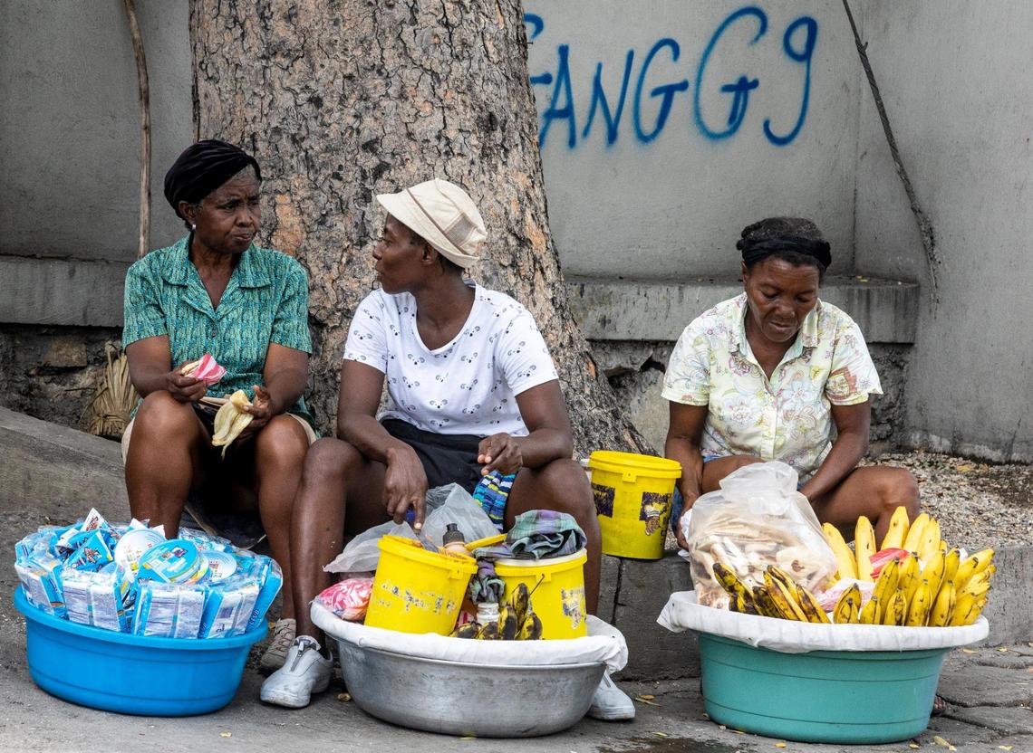 With gang graffiti scrawled on the wall behind them, women sell their wares on the street of Port-au-Prince on Tuesday, June 21, 2022.