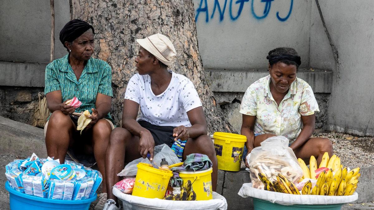 With gang graffiti scrawled on the wall behind them, women sell their wares on the street of Port-au-Prince on Tuesday, June 21, 2022.