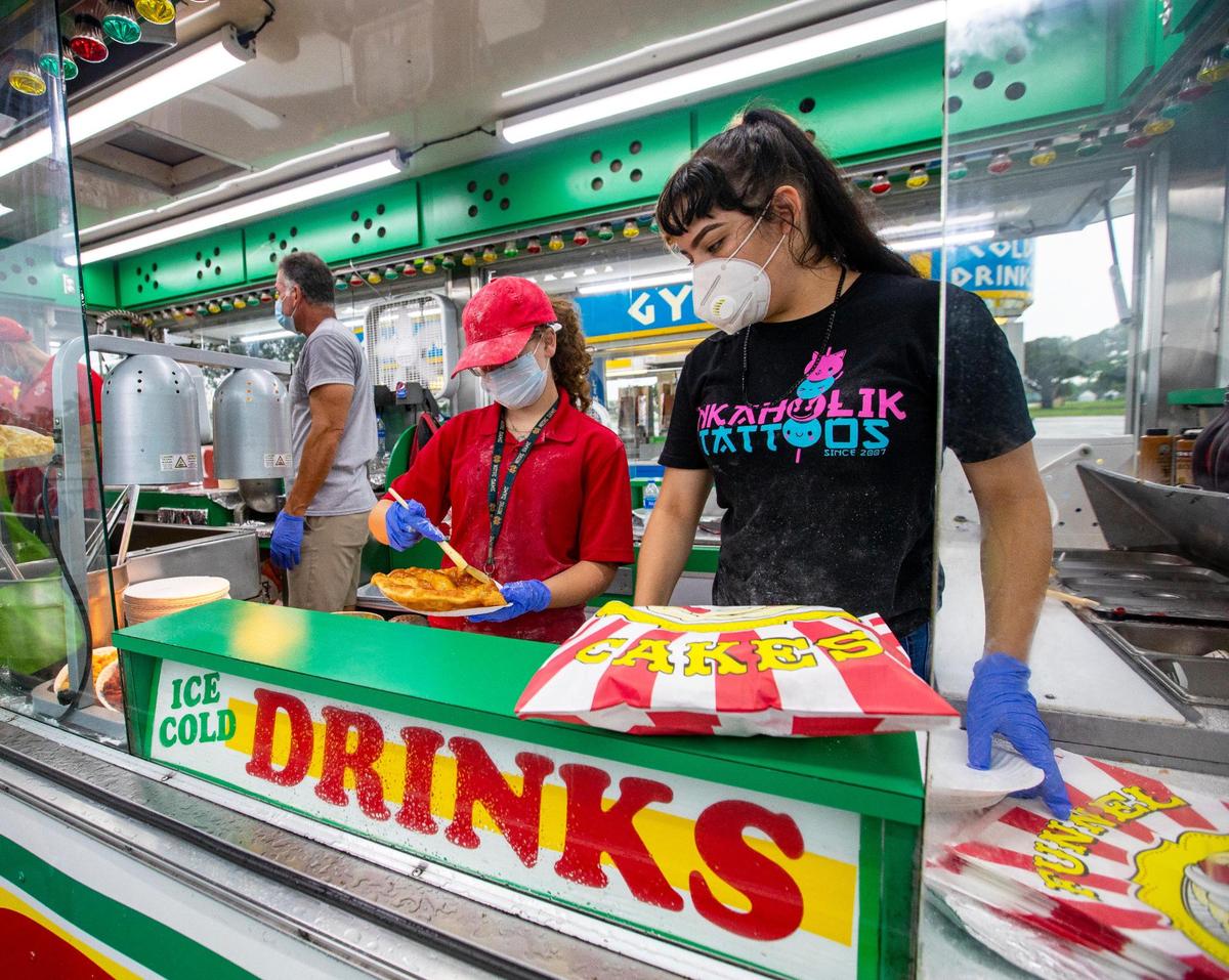 Food vendor employees Delaney Mcgrath, 14, and Fiorella Moreno, 18 prepare a elephant ear dessert during the Miami-Dade County Youth Fair food drive-through in Miami, Florida on Saturday, July 11, 2020.
