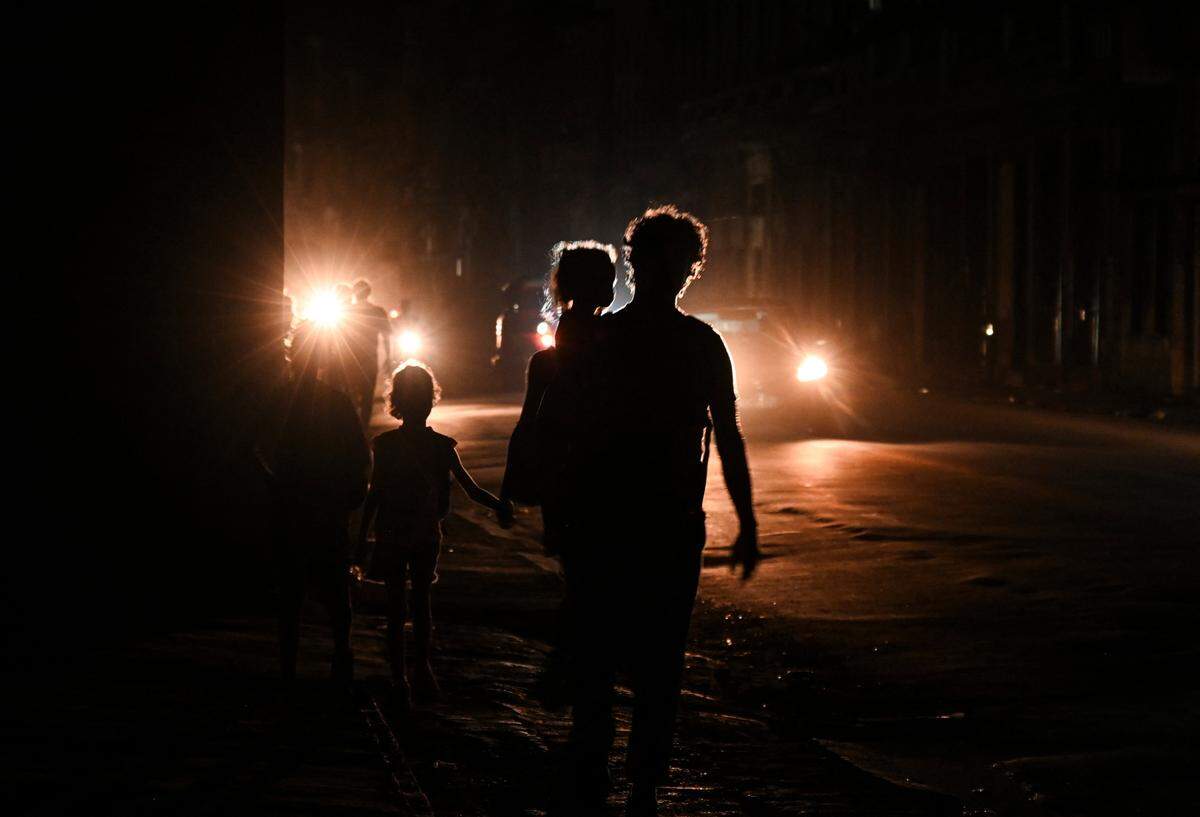 Cubanos caminan por una calle durante la tercera noche de un apagón nacional en La Habana el 20 de octubre de 2024. El apagón total que mantiene a la isla a oscuras desde hace tres noches.