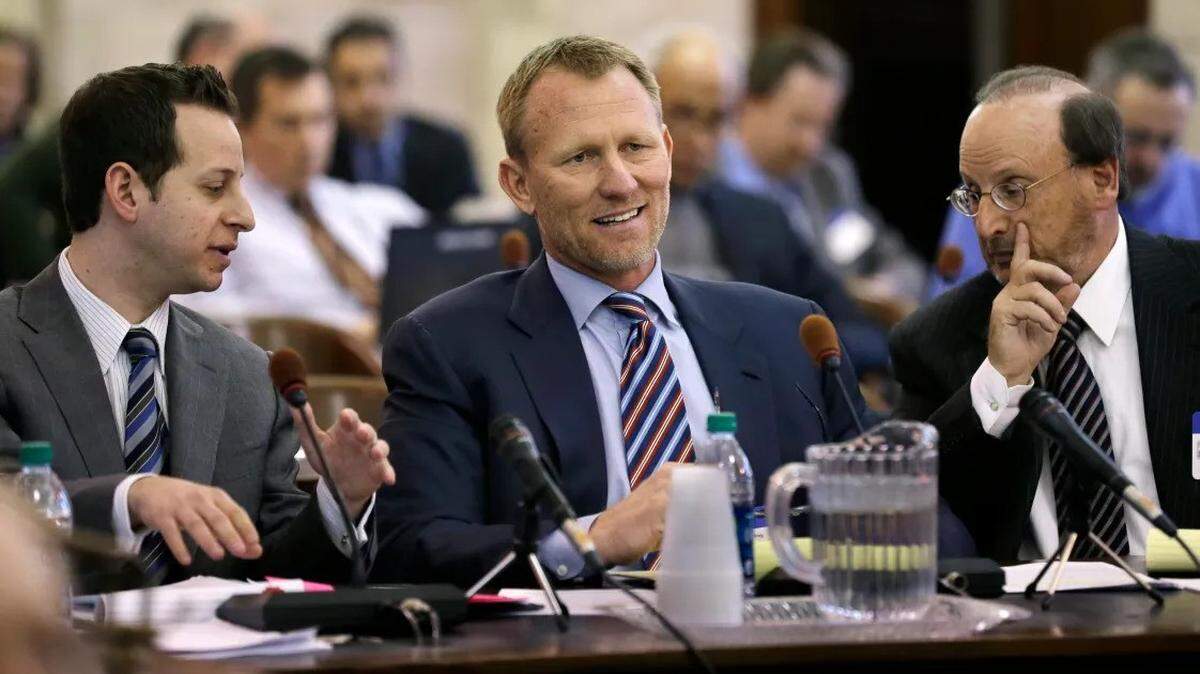 AshBritt founder Randy Perkins sits between attorneys Jared Moskowitz, left, who is now serving in Congress, and Michael Moskowitz, right, in 2013 as Perkins reacts to questioning in Trenton, N.J., from a member of a joint Senate-Assembly committee at the Statehouse.