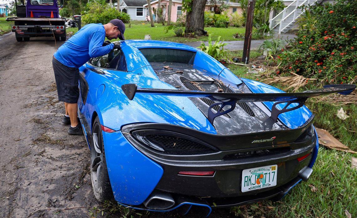 Tow-truck operator Eddie Cruz pulls on the window of a McLaren 720S as he notices water damage on Friday, October 11, 2024, in Port Charlotte, Florida, caused by Hurricane Milton’s storm surge. Cruz’s verdict — a total loss.
