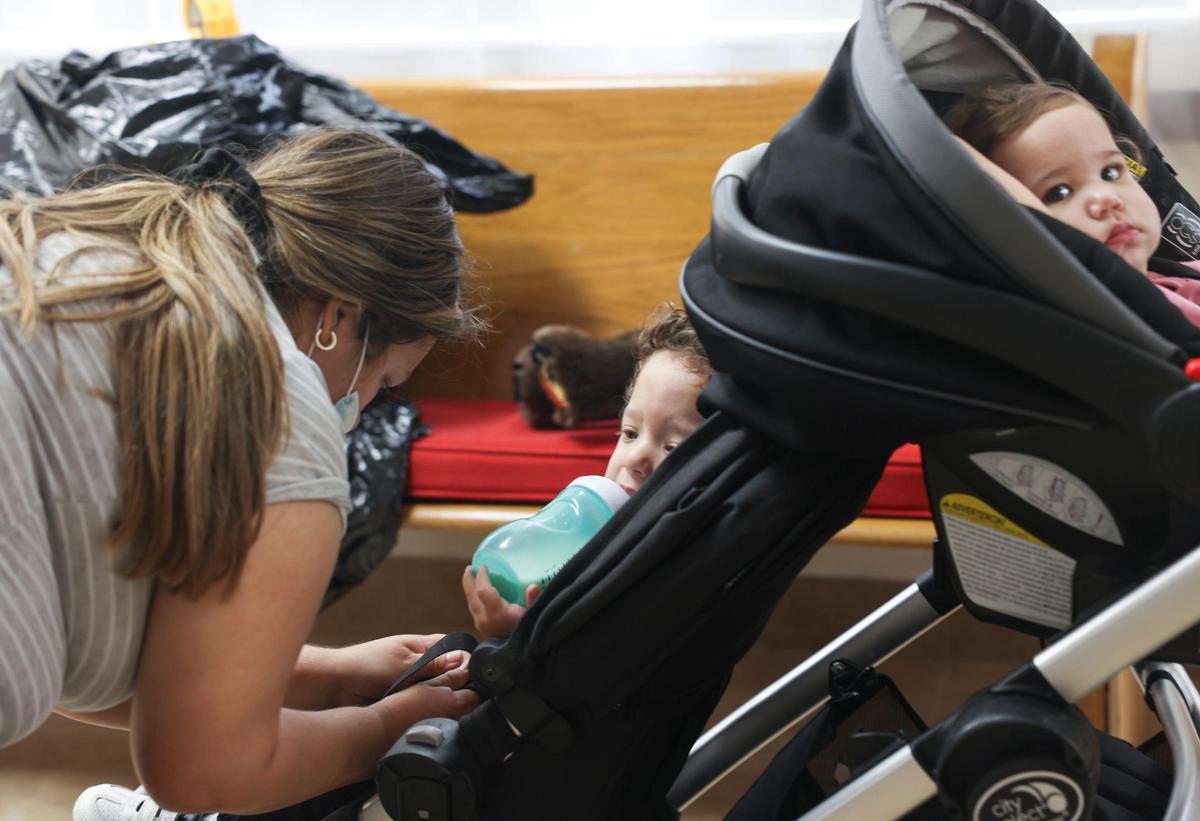 Leslie Castellanos, left, buckles up her son Ismael, 2, center, and daughter Isabelle, 11 months, after picking up baby formula in Coral Gables on Tuesday, May 24, 2022, at Tree of Life Parenting inside the Wesley Hispanic United Methodist Church. Isabelle is allergic to cow’s milk and needs hypoallergenic formula which is hard to find with the shortage. Catellanos’ son, Ismael, has a developmental disorder and needs special formula as well.