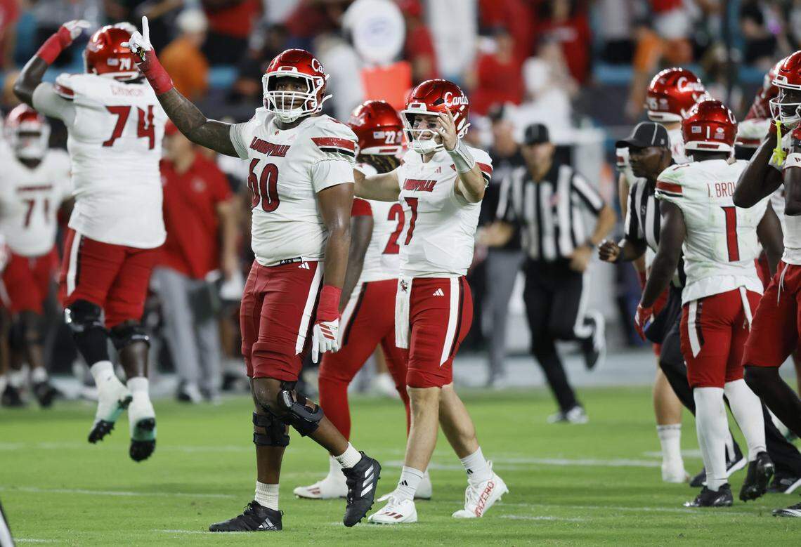 Louisville Cardinals offensive lineman Rasheed Miller (60) and quarterback Miller Moss (7) celebrate on the field with teammates after defeating the Canes during their NCAA football game at Hard Rock Stadium in Miami Gardens, Florida, on Friday, October 17, 2025.