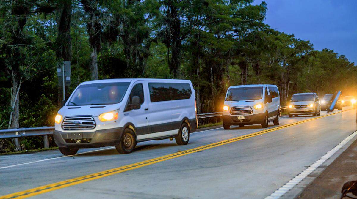 A motorcade of three white Ford vans followed by several sedans and other vehicles arrived at Alligator Alcatraz, the migrant detention center Florida has built in the Everglades, Wednesday night. The state said it was moving the first detainees to the site Wednesday evening.