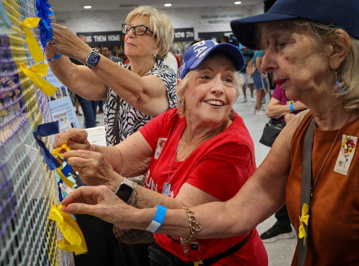 Thea Semanoff, 76, left, Ziba Bitton, 80, center, and Michelene Fayes, 77, right, place ribbons to create an art piece in solidarity with the hostages still in Hamas captivity. The Jewish Federation of Broward County held a community-wide event, marking the second anniversary of the tragic attacks in Israel on October 7, 2023, at the David Posnack Jewish Community Center in Davie.