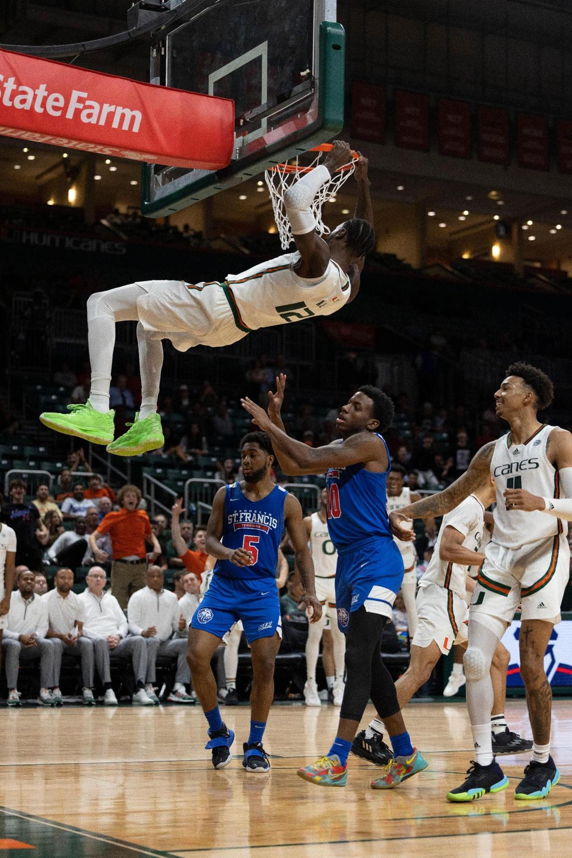 Miami center Favour Aire (12) hangs on the basket after dunking the ball during the second half of a NCAA men’s basketball game between the University of Miami Hurricanes and the St. Francis Brooklyn Terriers on Wednesday, Nov. 23, 2022, at the Watsco Center in Coral Gables. Miami won 79-56.