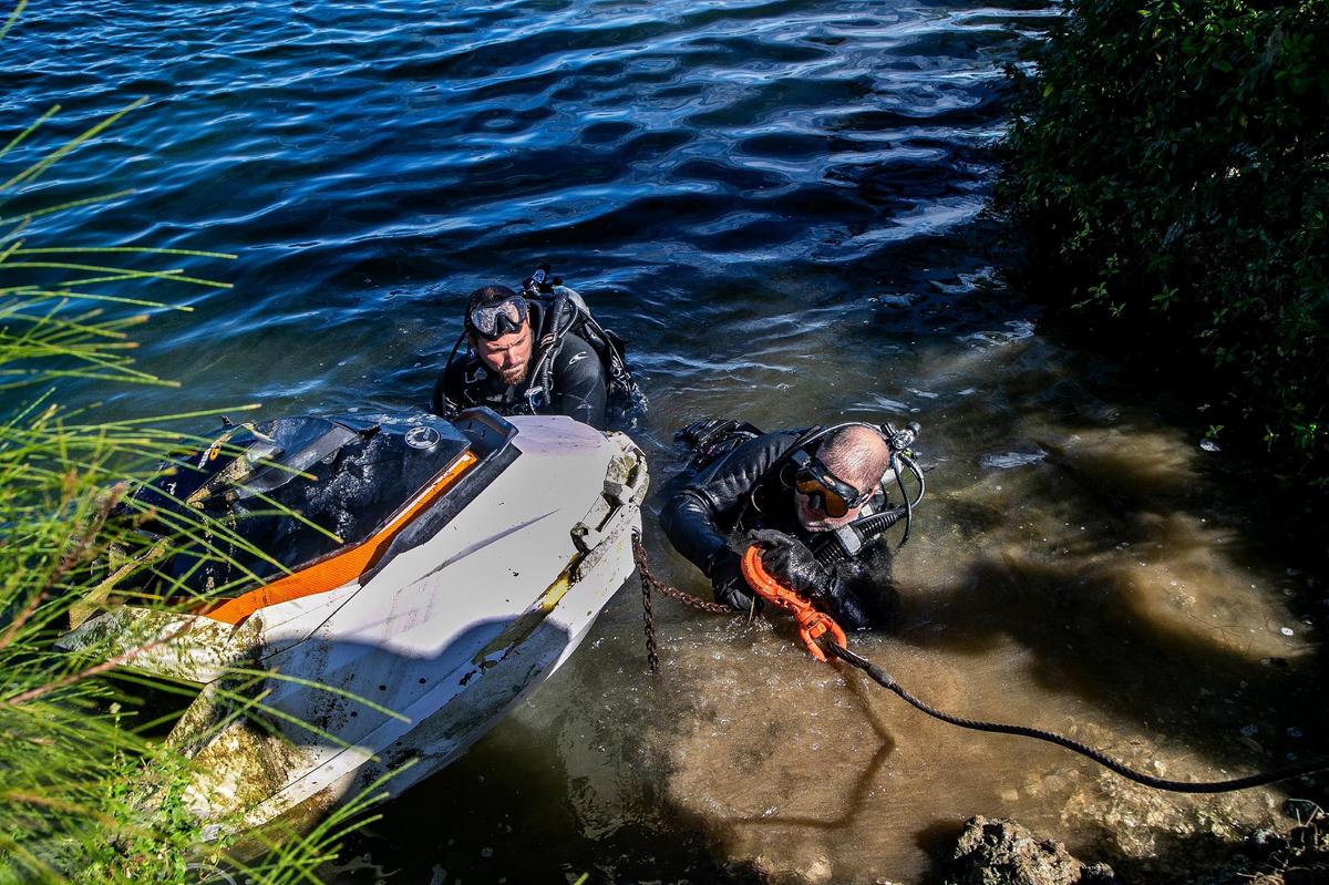 Divers Michael Mallon (right) and Peter Delgado, members of the Miami-Dade Police Marine Patrol Underwater Recovery Team, hooked up a Seadoo watercraft they found Tuesday in a lake in South Miami-Dade, with a punctured hole, which made it easier to sink. Its engine and other electrical parts had been stripped.