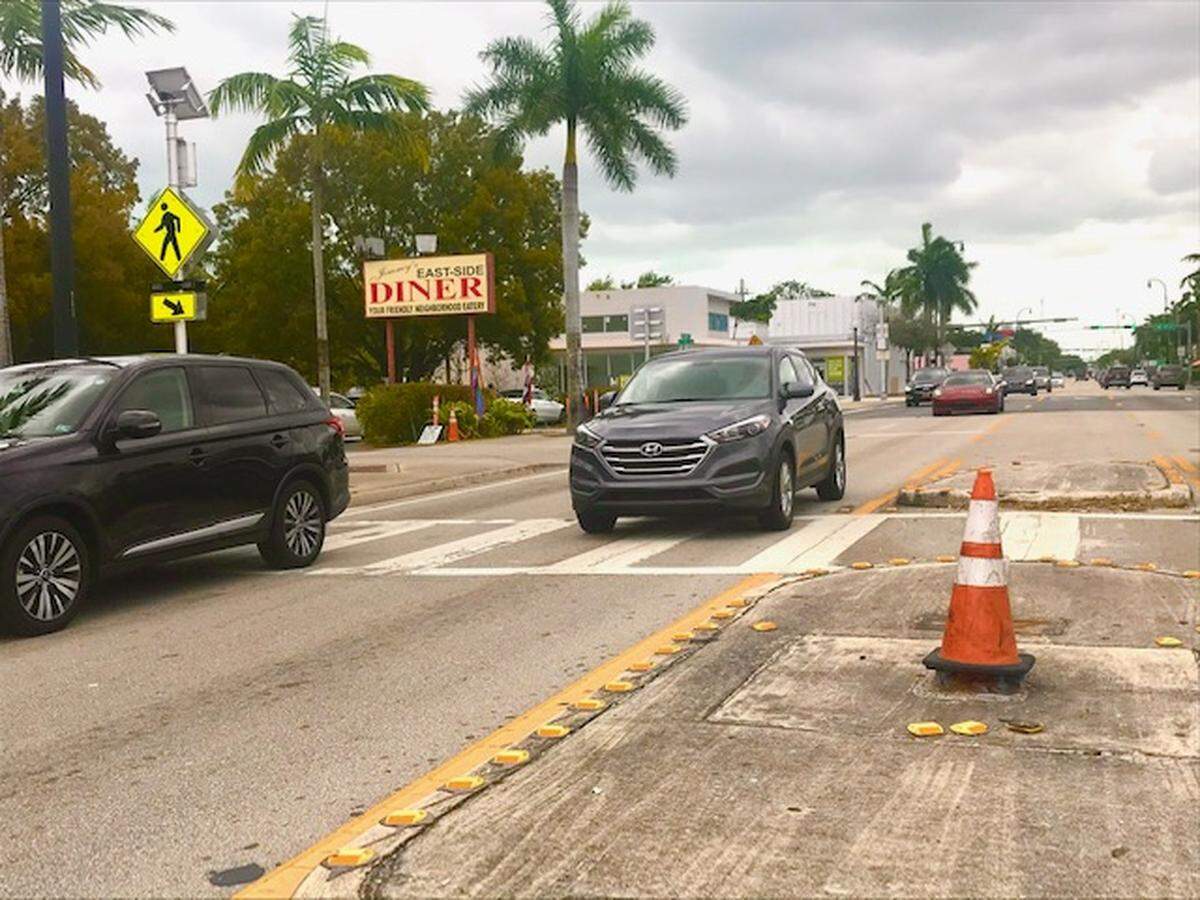 An orange cone sits over the spot where a flashing crosswalk signal existed until it was knocked down by an errant driver a year ago. This mid-block beacon on the median of 4-lane Biscayne Boulevard at NE 72nd Street still hasn’t been replaced, despite pleas from the public.