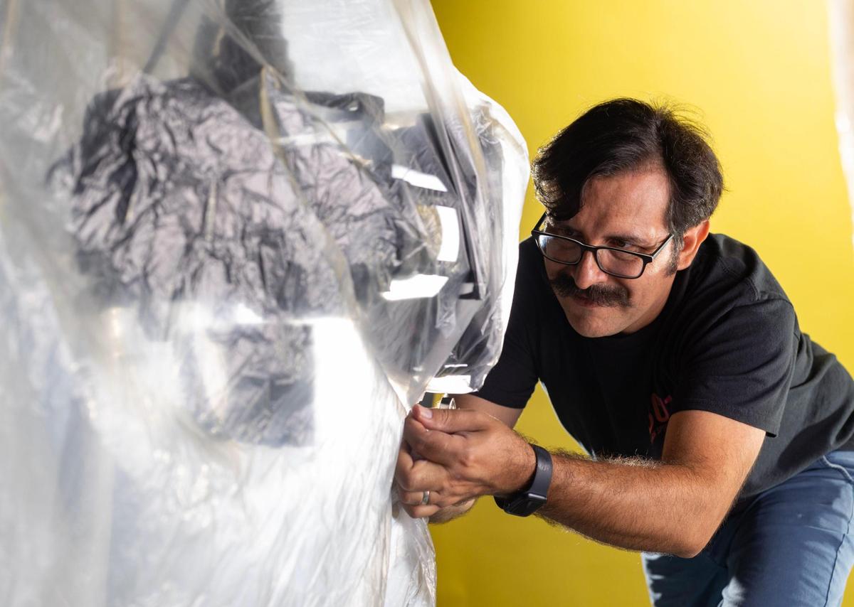 Aguila covers the robot with a sheet to protect it from water during a demonstration of how the robot works.