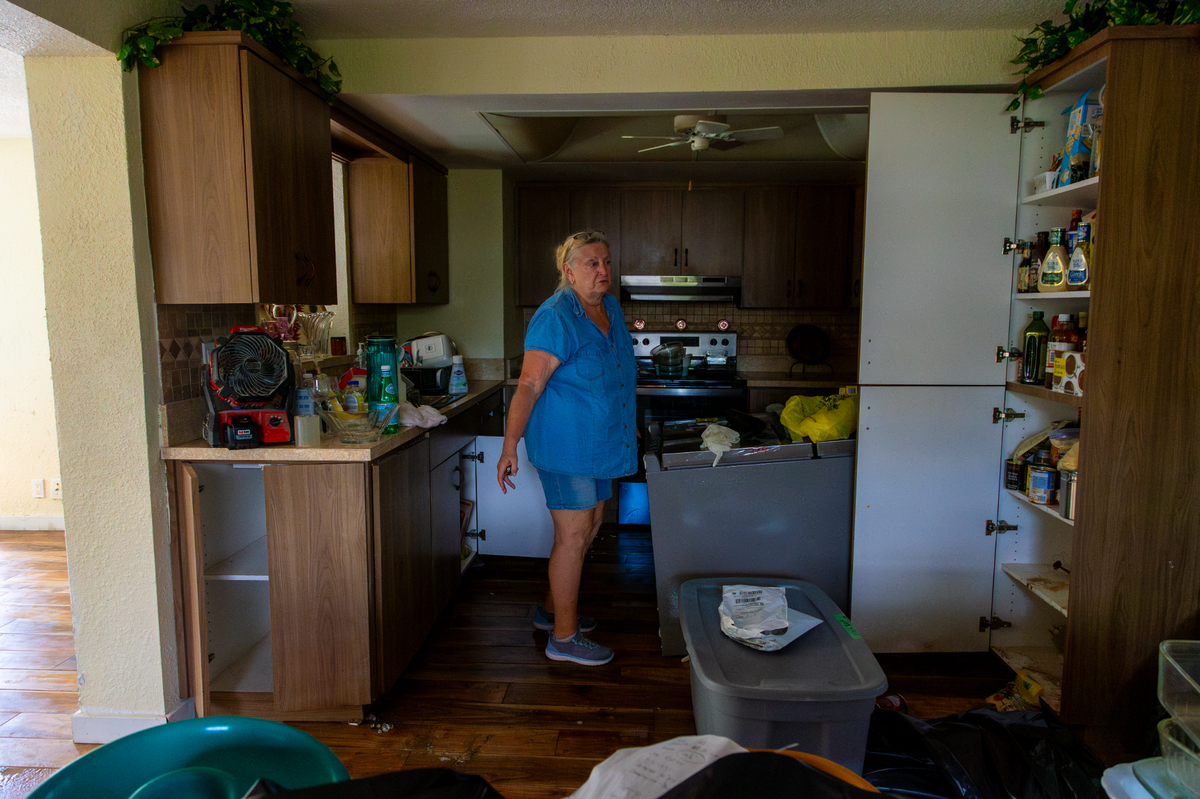 Dawn Kremer shows how the power of storm surge from Hurricane Helene knocked over her refrigerator and filled her cabinets with water in her Saint Petersburg home.