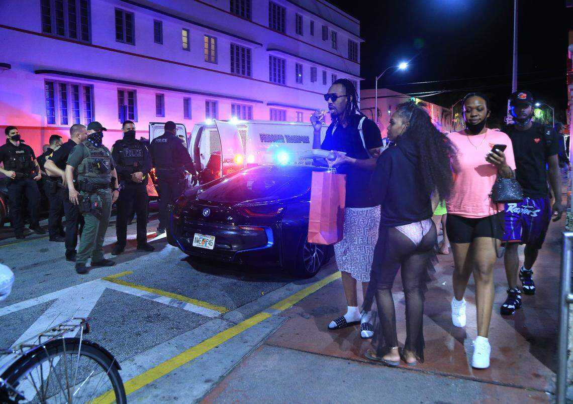 People watch as City of Miami Beach Police officers arrest several males on Ocean Drive and 10th Street as spring break officially began and the city expected thousands of tourists to visit South Beach, escaping cold weather and harsh COVID-19 restrictions on Saturday, February 20, 2021.