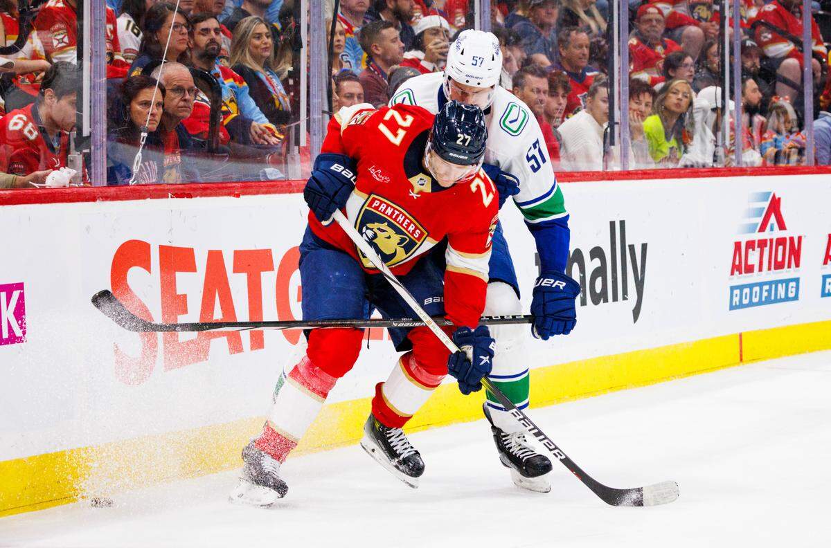Florida Panthers center Eetu Luostarinen (27) tries to keep the puck from Vancouver Canucks defenseman Tyler Myers (57) during the third period of a game on Thursday, Oct. 17, 2024, at Amerant Bank Arena in Sunrise, Fla.
