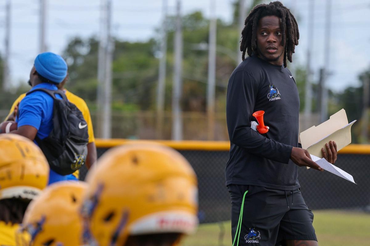Northwestern football coach Teddy Bridgewater, right, former Miami Dolphins quarterback, hands out practice notes while walking on the field during the Northwestern football practice on Monday, April 29, 2024 in Miami, Florida.