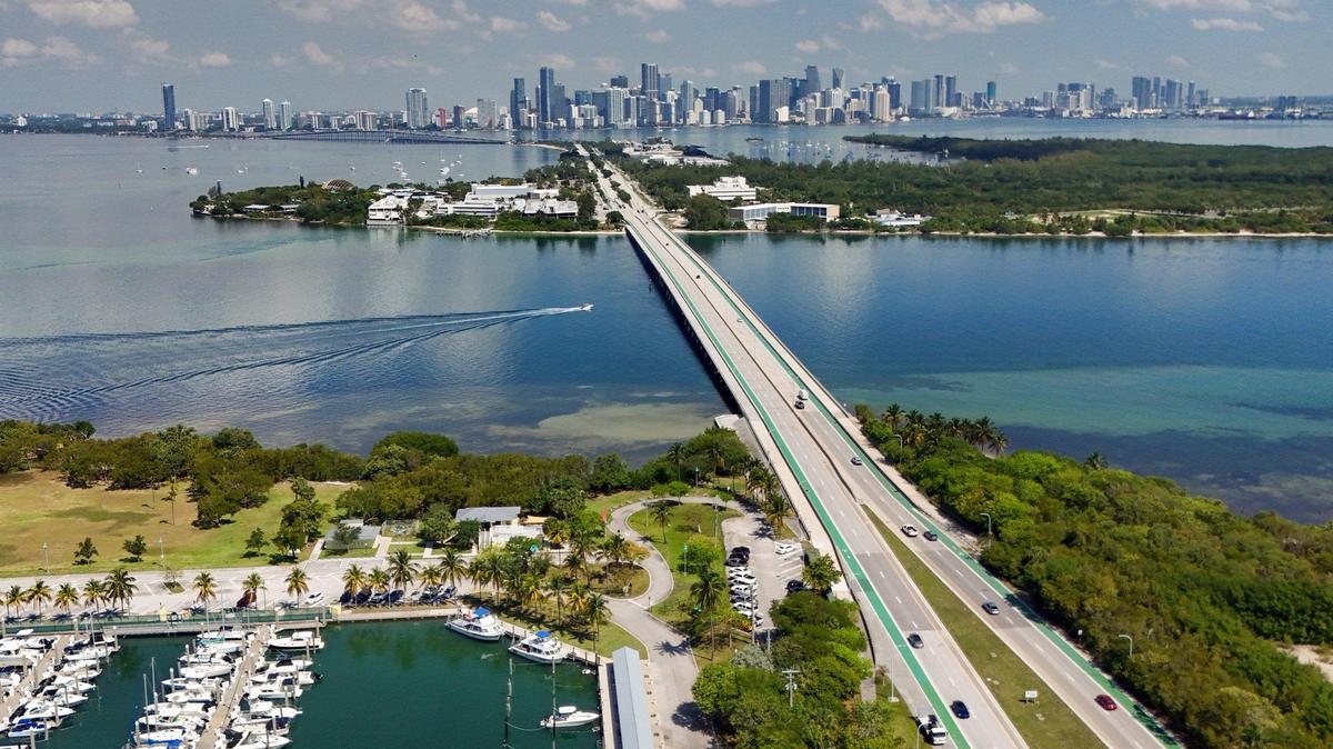 The Bear Cut bridge connects Key Biscayne and the Crandon Park marina, bottom left, and Bear Cut Preserve, bottom right, to the Rickenbacker Causeway and Virginia Key, top center. The downtown Miami and Brickell skyline is visible in the background.