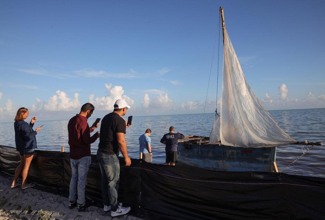 Passersby leave their cars to take pictures of a small Cuban sailboat abandoned on U.S. 1 just north of Marathon in the Florida Keys. On Wednesday, Jan. 4, 2023, about 40 men, women and some small children entered the next stage in their migration from Cuba to the United States when they were processed by the Border Patrol at the agency’s station in Marathon in the Middle Keys. They were among hundreds of people from Cuba, and one large group of over 100 men and women from Haiti, who’d landed across the island chain since the end of the previous week.