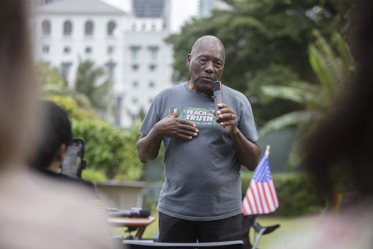 Activist and historian Marvin Dunn speaks with protesters about Miami's history outside the Kaseya Center, where former President Donald Trump made an appearance. Demonstrators carried signs and chanted against his policies and a proposed land transfer for Trump's presidential library. The protest took place in Miami on Wednesday, Nov. 5, 2025.