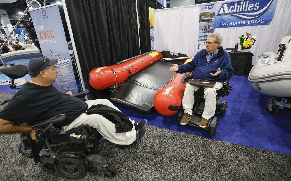 Juan Garcia and Harry Horgan, left to right, discuss the prototype of the Achilles inflatable boat intended for use by the disabled and rescue operation and on display at the Miami Beach International Boat Show in the Miami Beach Convention Center on Miami Beach, Florida on Thursday, February 12, 2026.