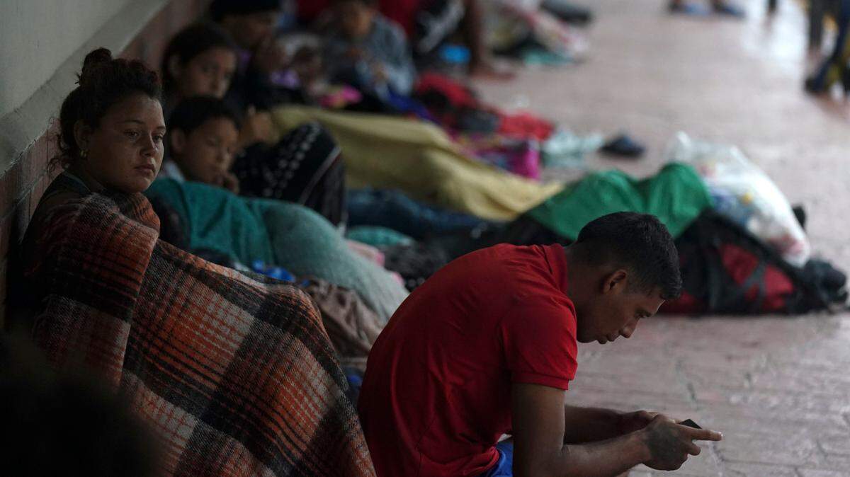 Venezuelan migrants sit along a building wall as they take cover from the rain, near the banks of the Rio Grande in Matamoros, Mexico, Saturday, May 13, 2023. As the U.S. ended its pandemic-era immigration restrictions, migrants are adapting to new asylum rules and legal pathways meant to discourage illegal crossings.