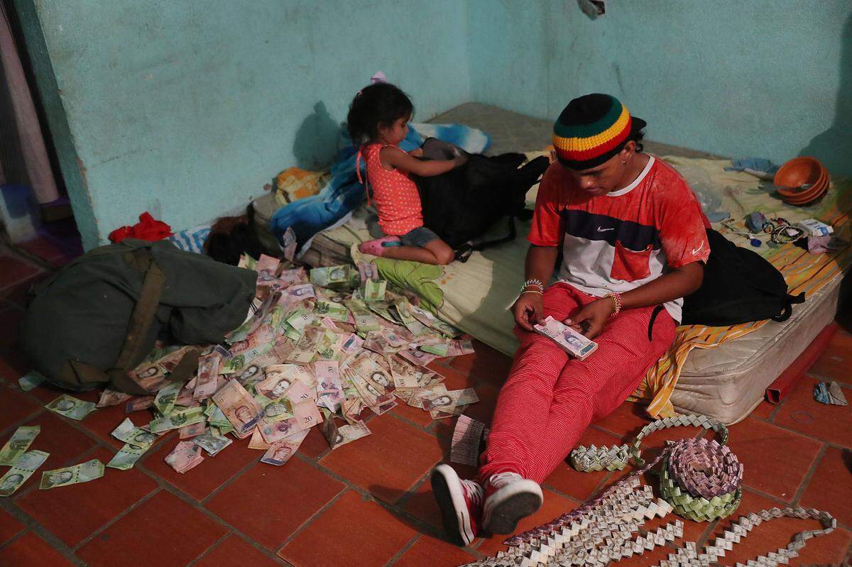 Jorge Corbero, originally from Caracas, Venezuela, sits on his bed as he uses the Venezuela bolívar, which has such little value, to make purses and other items to sell on the street.