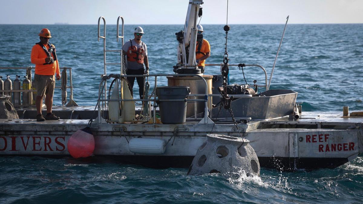 A barge lowers a “reef ball” containing the ashes of Capt. James O. Gilson into the ocean during a ceremony on Monday, March 27, 2023 at the Golden Beach Reef Site Near Haulover Beach. Eternal Reefs is a company that works with families to turn the ashes of their loved ones into artificial reefs.