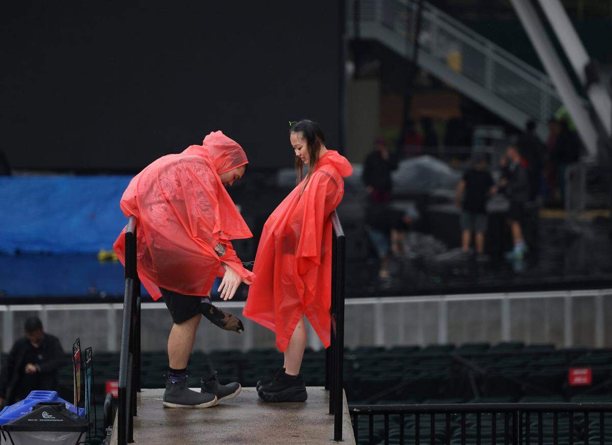 One festival-goer wipes mud off his sock after the storm during the third day of Ultra Music Festival on Sunday, March 30, 2025, at Bayfront Park in downtown Miami, Fla. The festival closed its doors for about a half hour urging fans to take cover from the lightning and rain, but then opened back up after it passed.  