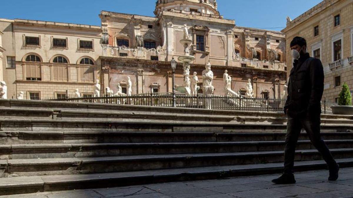 A man wearing a face mask walks in vacant Pretoria square in Palermo, Italy. Tourism represents 13 percent of the country’s annual GDP.