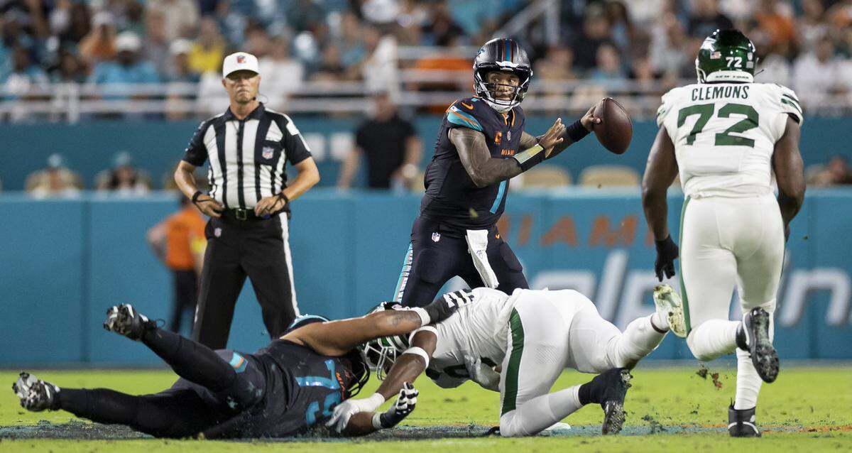 Miami Dolphins quarterback Tua Tagovailoa (1) looks to pass the ball as New York Jets defensive end Micheal Clemons (72) defends in the first half of their NFL game at Hard Rock Stadium on Monday, Sept. 29, 2025, in Miami Gardens, Fla.