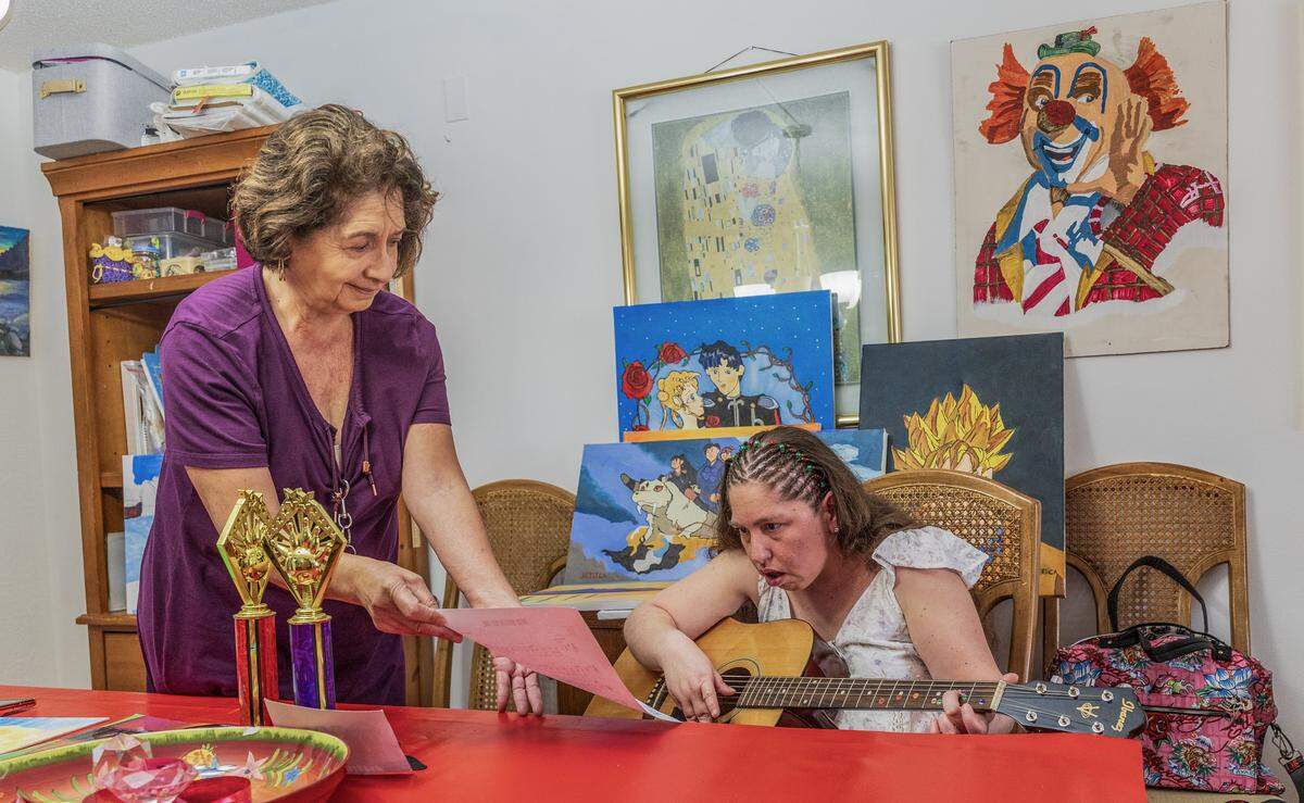 Rita Acosta holds a music score as her daughter Jessica Novoa, plays the guitar. Jessica is in her 40s and suffers from epilepsy since she was a little girl and a brain surgery some time ago as she continues to battle epilepsy. At her house, in Sunrise, Florida, on Saturday, December 13, 2025.