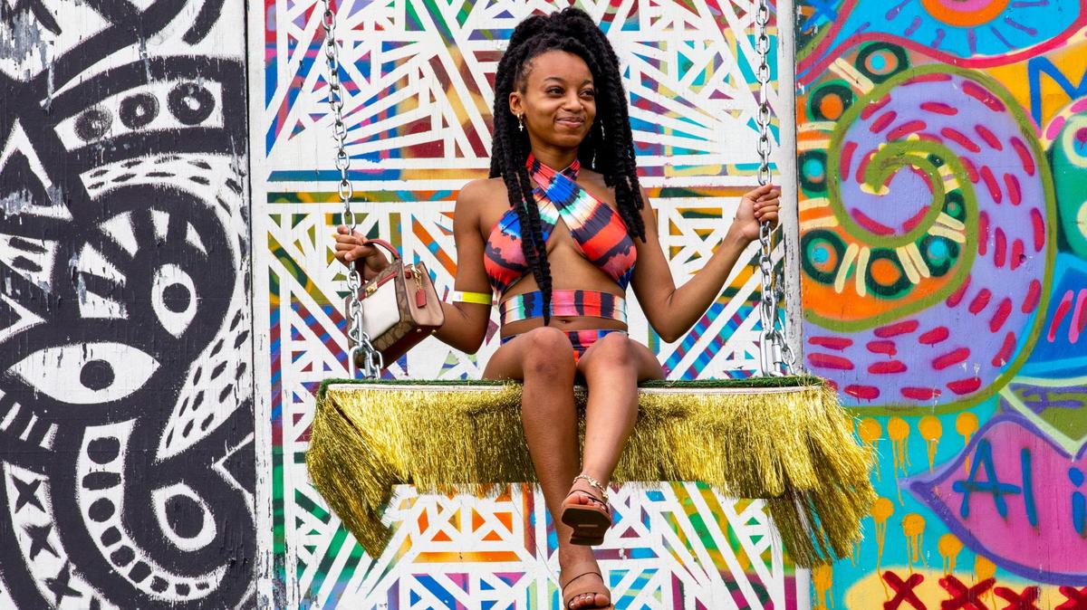 Miami resident Maya Diaz, 22, swings from an art installation during AFROPUNK music festival at The Urban in the Historic Overtown neighborhood of Miami, Florida, on Saturday, May 21, 2022.