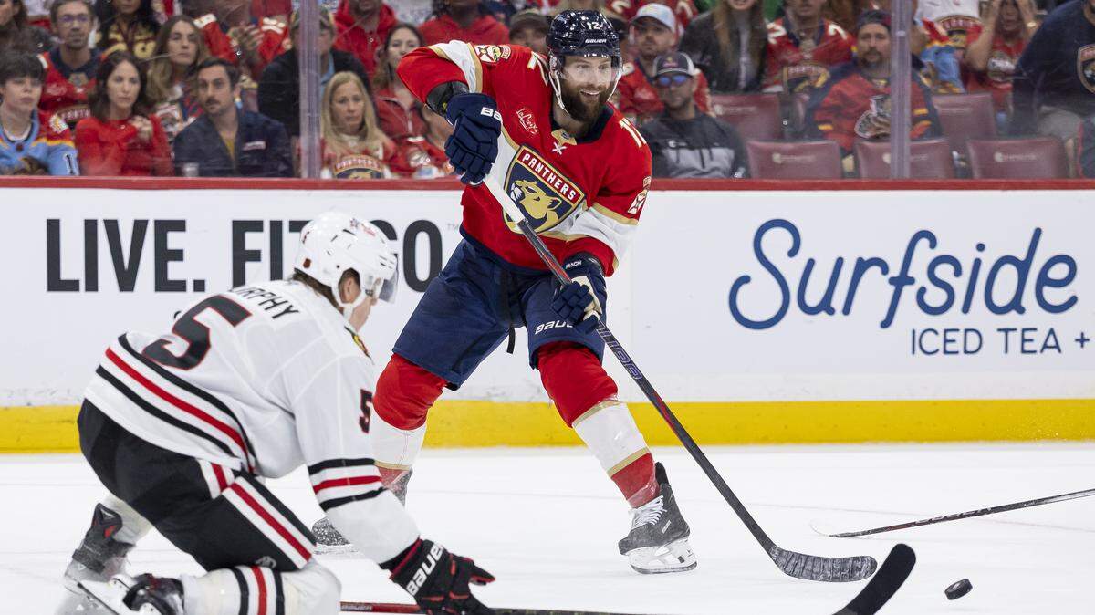Florida Panthers left wing Jonah Gadjovich (12) passes the puck as Chicago Blackhawks defenseman Connor Murphy (5) defends in the third period of their NHL game at Amerant Bank Arena on Tuesday, Oct. 7, 2025, in Sunrise, Fla.