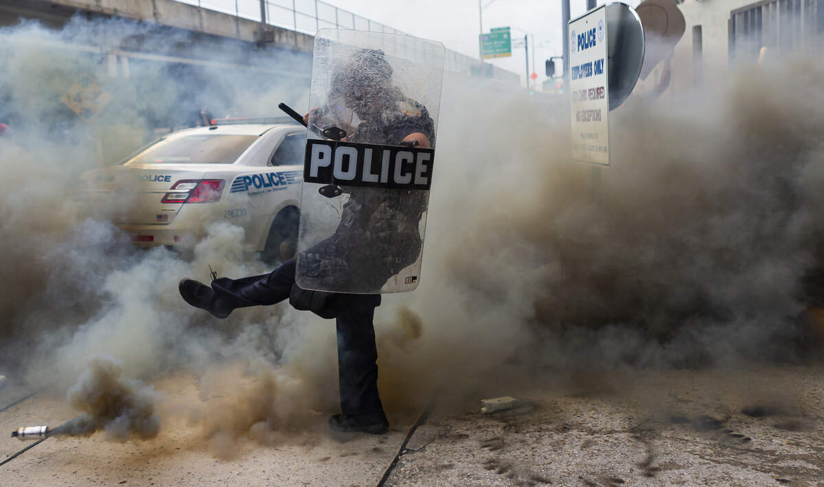 Un policía patea una granada de humo durante una protesta en el downtown de Miami el sábado 30 de mayo de 2020.