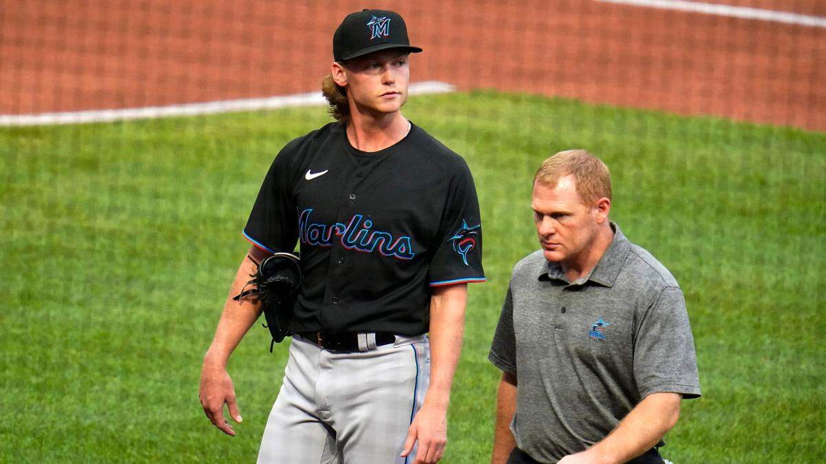 Miami Marlins starting pitcher Max Meyer, left, walks off the field with a team trainer after throwing 10 pitches in the first inning during a baseball game against the Pittsburgh Pirates in Pittsburgh, Saturday, July 23, 2022. The Pirates won 1-0.