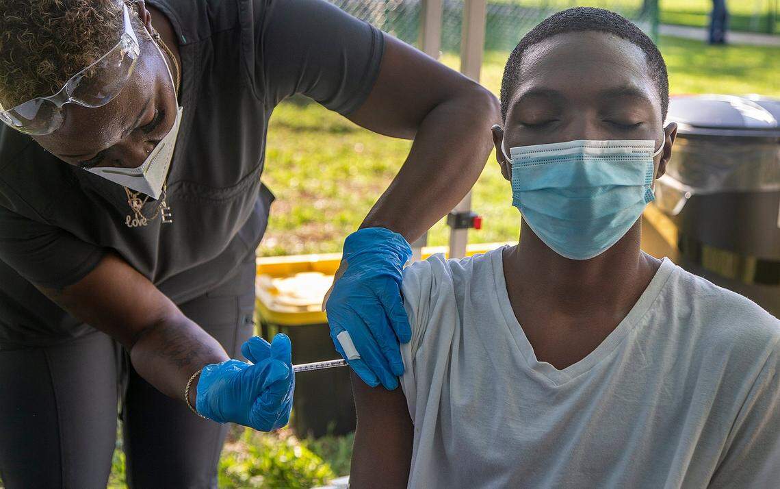 Tyler Cooper, 13, gets his first Pfizer COVID-19 shot from Nurse Erica Goodin at the South Miami Children’s Clinic, as part of a Pfizer pop-up in partnership with Miami-Dade County, hosted by Dr. Tina Carroll-Scott at the clinic, on Saturday, May 15, 2021.