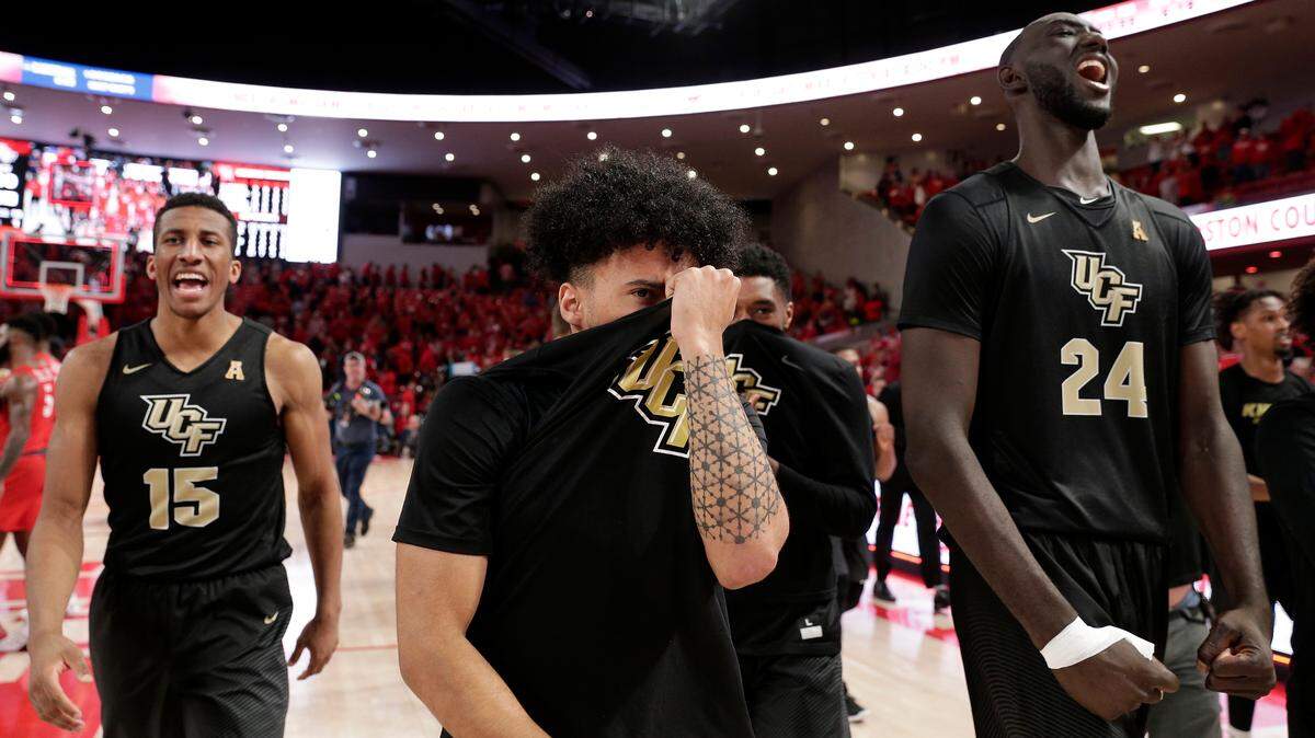 Central Florida guard Aubrey Dawkins (15), guard Levy Renaud, center, and center Tacko Fall (24) celebrate after their upset of Houston on Saturday.