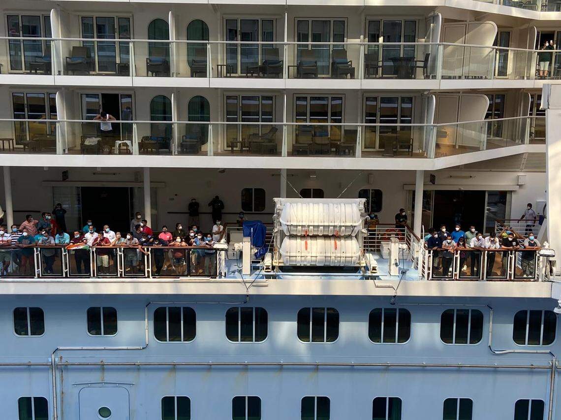 Crew members on Royal Caribbean’s Anthem of the Seas ship look out at the Oasis of the Seas ship as crew transfer between the ships at the company’s private islands in the Bahamas on May 8, 2020.